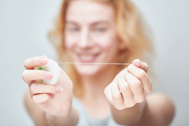 young woman holding floss since she learned how to floss properly