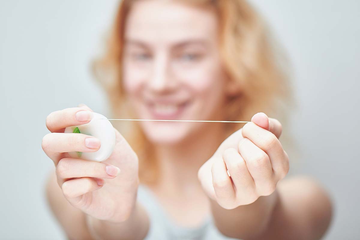 young woman holding floss since she learned how to floss properly