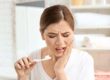 woman trying to brush her teeth but realizing she has tooth decay