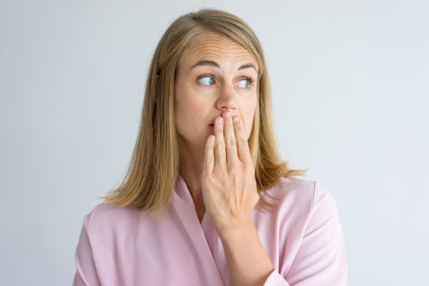 causes of bad breath (3) woman covering her mouth to prevent the causes of bad breath