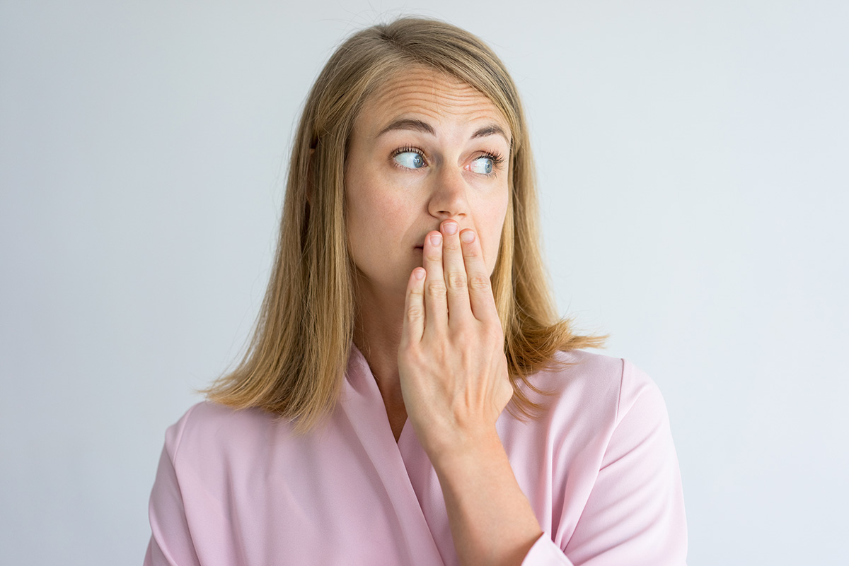 causes of bad breath (3) woman covering her mouth to prevent the causes of bad breath