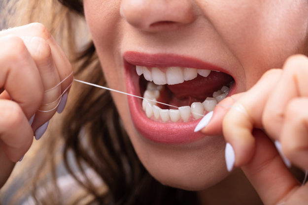 a woman flossing after learning the benefits of flossing daily